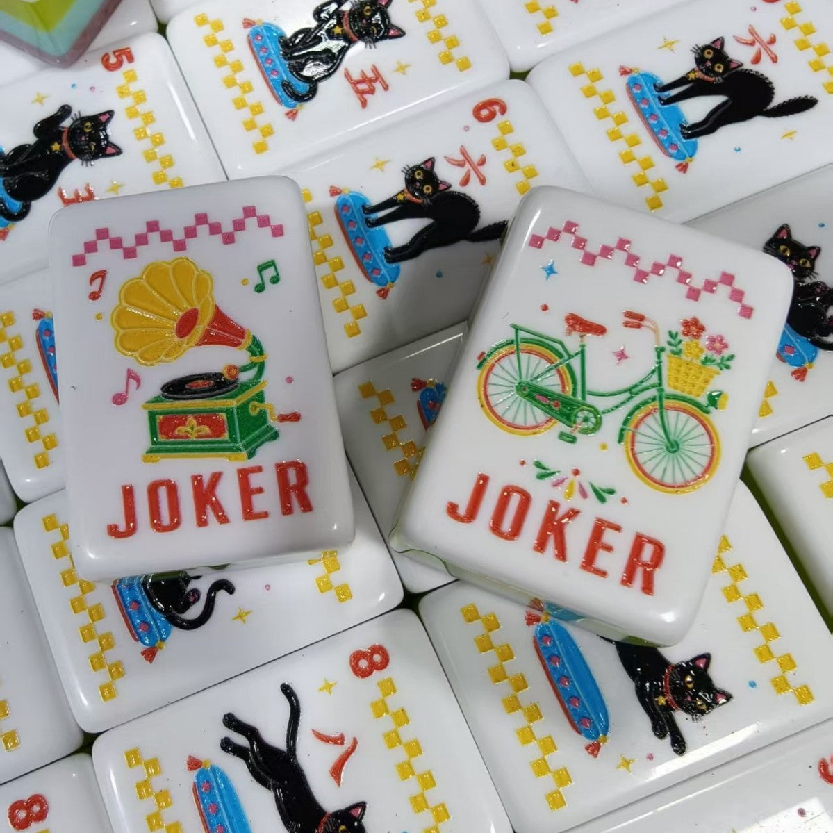Overhead shot of Retro Nostalgia mahjong tiles, pink pearlescent marble backs, radio and telephone jokers, butterfly flower tiles, umbrella bamboo tiles 1-9 and hot air balloon dot tiles 5-9, aqua-lime-pink layered side stripes