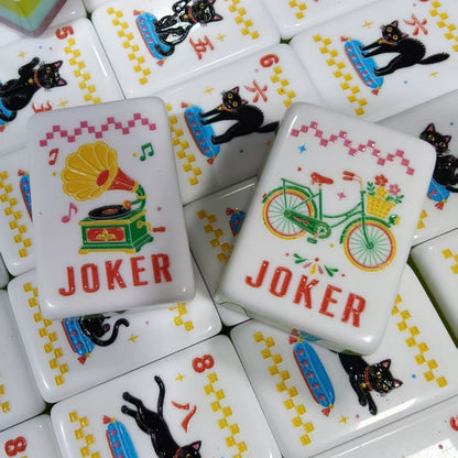 Overhead shot of Retro Nostalgia mahjong tiles, pink pearlescent marble backs, radio and telephone jokers, butterfly flower tiles, umbrella bamboo tiles 1-9 and hot air balloon dot tiles 5-9, aqua-lime-pink layered side stripes