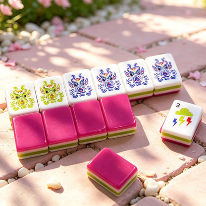 Overhead scattered pile of Strawberry Bow mahjong tiles on white background, showing glossy hot pink backs, colorful striped edges, white tile faces with strawberry heart, green bow and fruit number illustrations