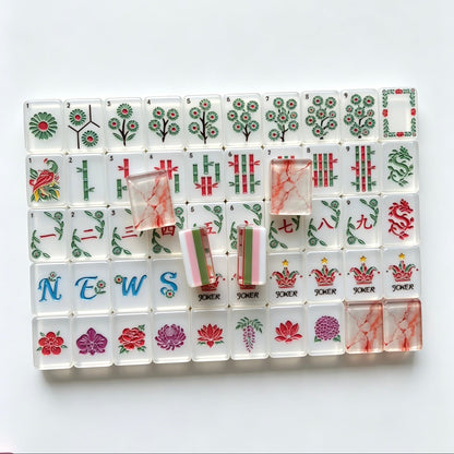 Flat lay of Pink Marble Floral American mahjong tiles arranged neatly on clean white background, white tile fronts with green floral dot patterns, classic bamboo, red dragons, multi-color flower tiles and crown jokers