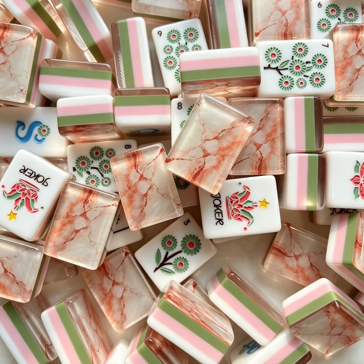 Flat lay of Pink Marble Floral American mahjong tiles arranged neatly on clean white background, white tile fronts with green floral dot patterns, classic bamboo, red dragons, multi-color flower tiles and crown jokers
