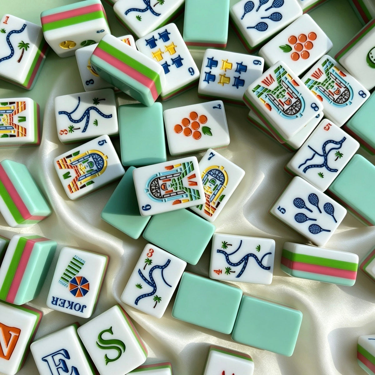 Neat full layout of Tropical Golf Resort American mahjong tiles, mint green tile backs, pink-green striped sides, custom golf, palm tree and resort building illustrations, arranged on light speckled countertop