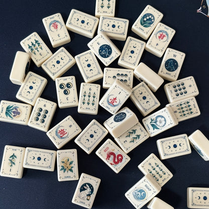 Side view of Moon Rabbit Tarot mahjong tiles lined up on acrylic rack over dark navy velvet fabric, cream ivory tiles with tarot border design, moon & star dots, floral bams, Chinese character cracks and moon rabbit lantern joker tile